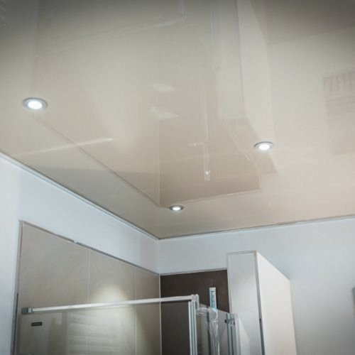 Die Decke eines modernen Badezimmers mit glänzender Oberfläche und integrierten LED-Lichtern, die eine helle Atmosphäre schaffen.