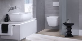 Ein modernes Badezimmer mit einer eleganten weißen Waschschüssel und einem stilvollen schwarzen Hocker im Hintergrund.