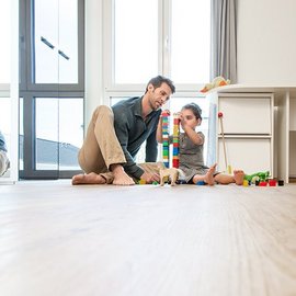 Ein Maedchen und ein Mann sitzen auf dem Boden und spielen 