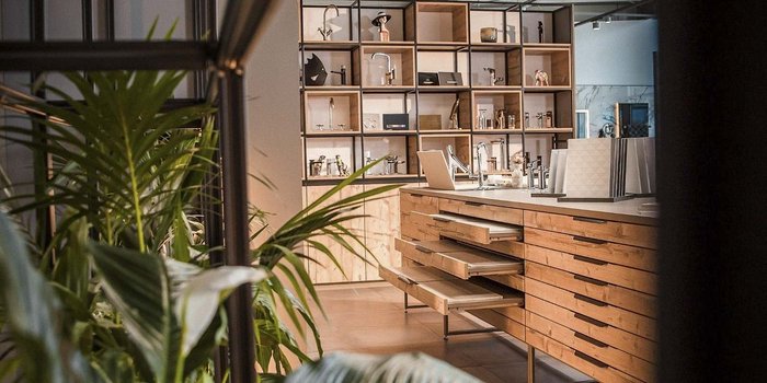 Ein moderner Ausstellungsraum mit Holzregalen, die stilvolle Armaturen und Dekorationsobjekte präsentieren.