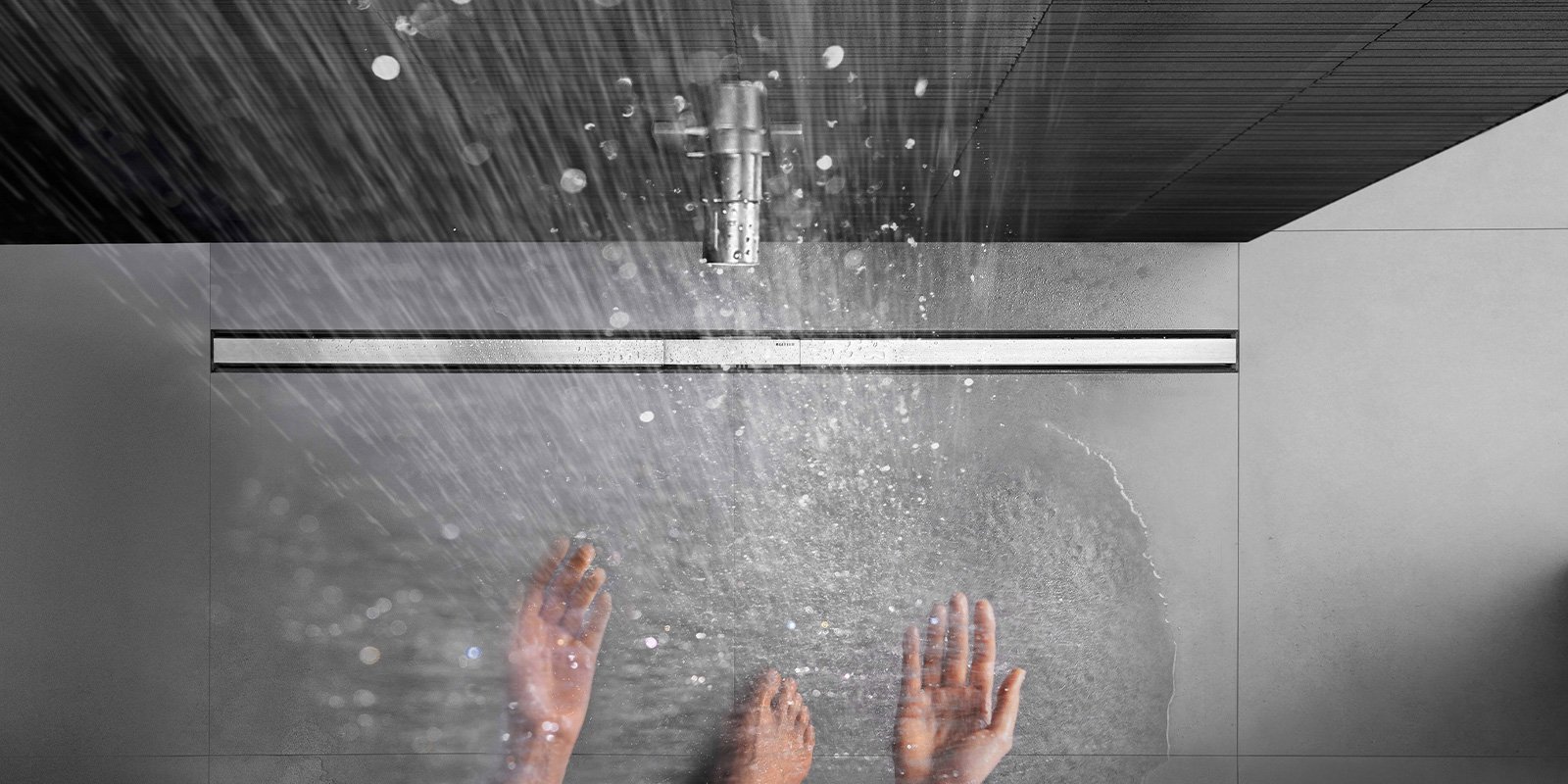 Die Hände einer Person fangen das Wasser auf, das aus einer eleganten Duschbrause strömt, umgeben von minimalistischen Fliesen.