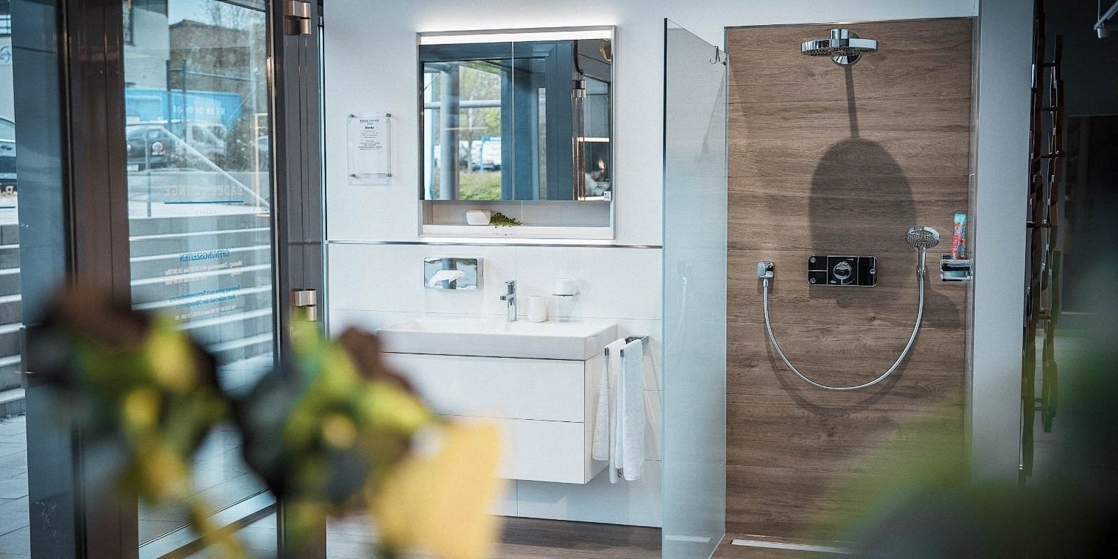 Ein modernes Badezimmer mit einem eleganten Waschbecken und einem großen Spiegel, der das Licht reflektiert.