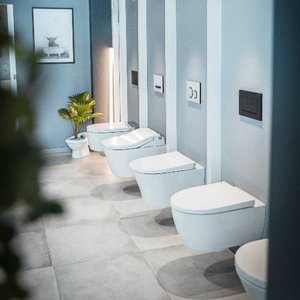 Ein modernes Badezimmer mit mehreren eleganten Toiletten, die an einer hellblauen Wand angeordnet sind.
