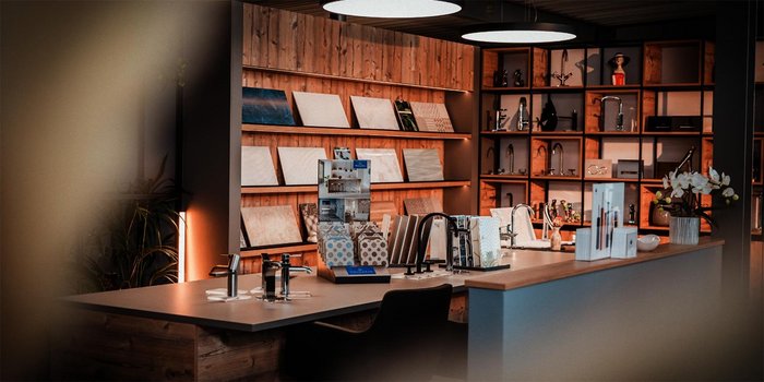 Ein eleganter Ausstellungsraum mit Holzregalen, die verschiedene Materialien und Küchenaccessoires präsentieren.