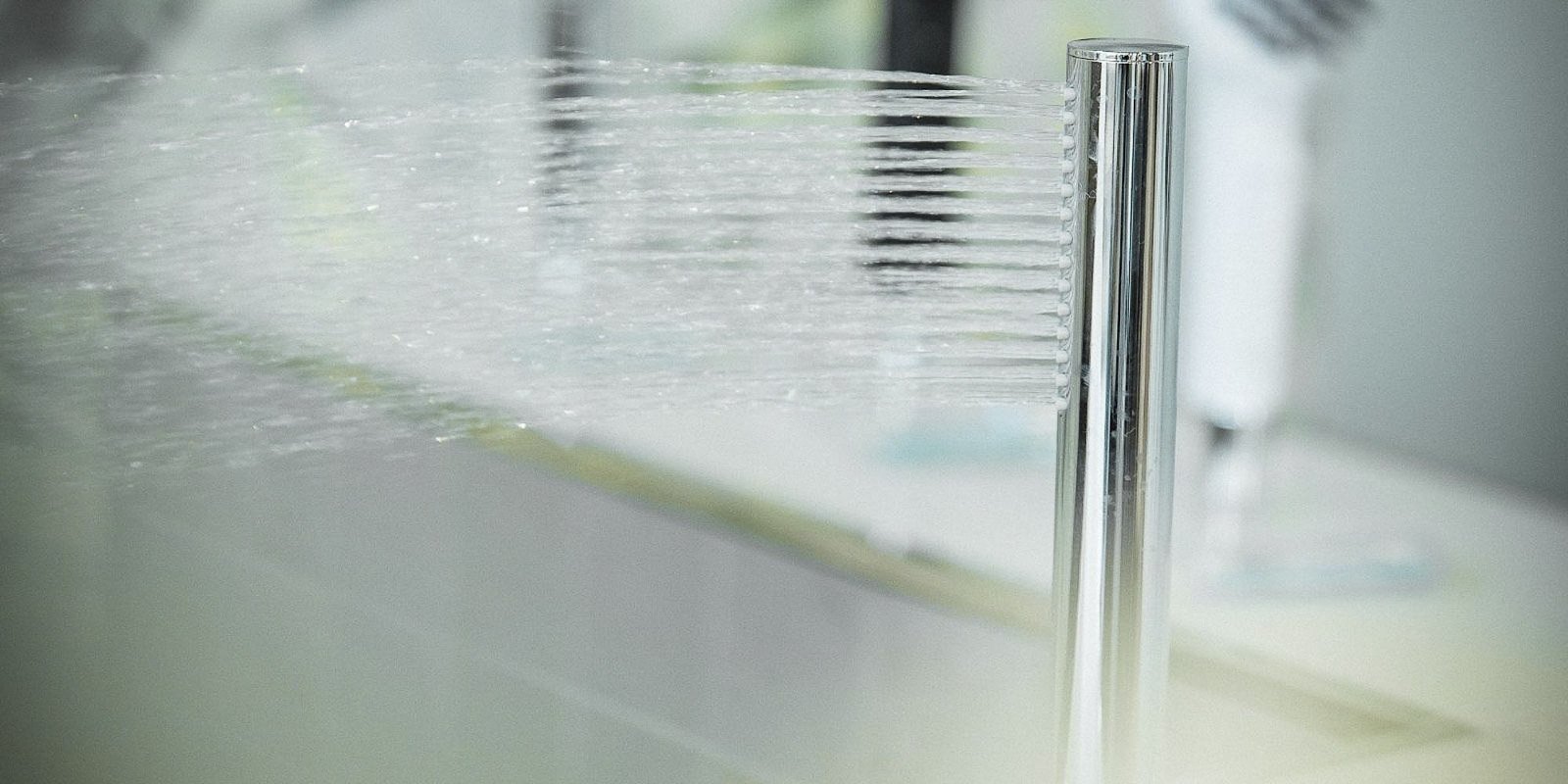 Ein glänzender Wasserhahn spritzt frisches Wasser in einem modernen Badezimmer, umgeben von einem hellen, minimalistischen Design.