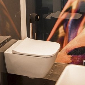 Ein modernes Badezimmer mit einem weißen Wand-WC und einem eleganten Waschbecken im Hintergrund.