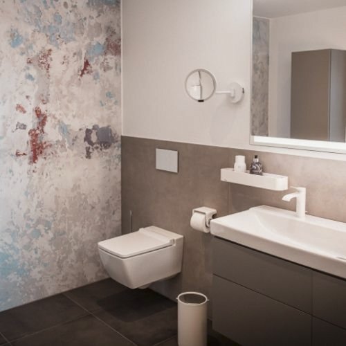 Ein modernes Badezimmer mit einer stilvollen Wandgestaltung und einem eleganten Waschbecken, das gut beleuchtet ist.
