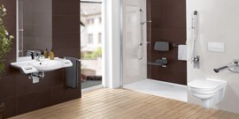 Ein modernes Badezimmer mit einem weißen Waschbecken, einem großen Spiegel und einer Dusche mit Glasabtrennung.